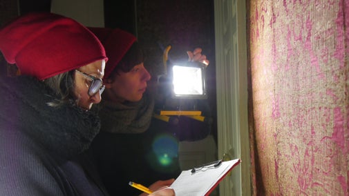 Two conservators examine wall hangings at The Vyne.